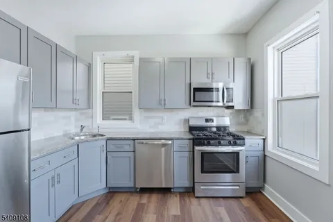 a kitchen with cabinets stainless steel appliances a sink and wooden floor
