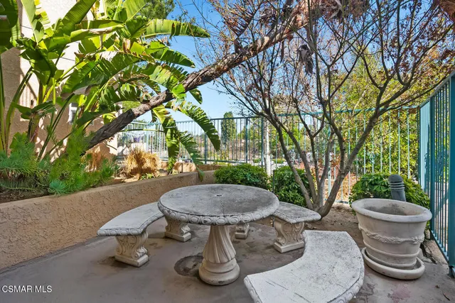 a view of a patio with table and chairs potted plants and large tree