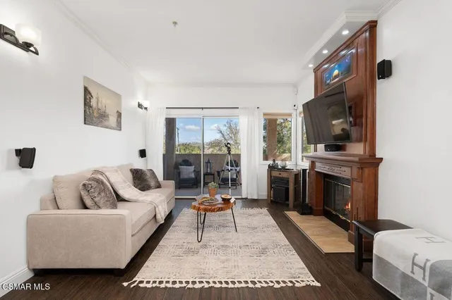 a living room with furniture a rug a flat screen tv and a refrigerator