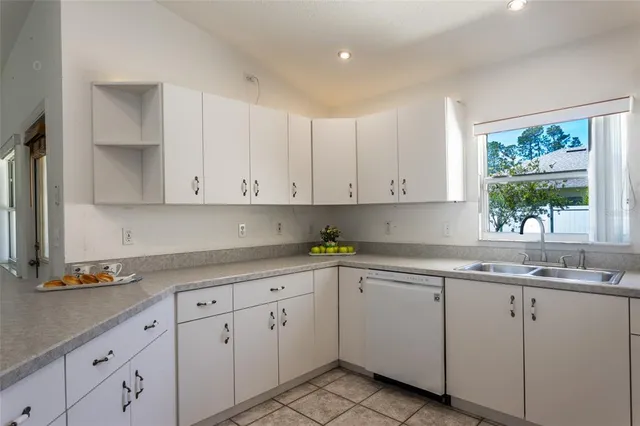 a kitchen with white cabinets sink and window
