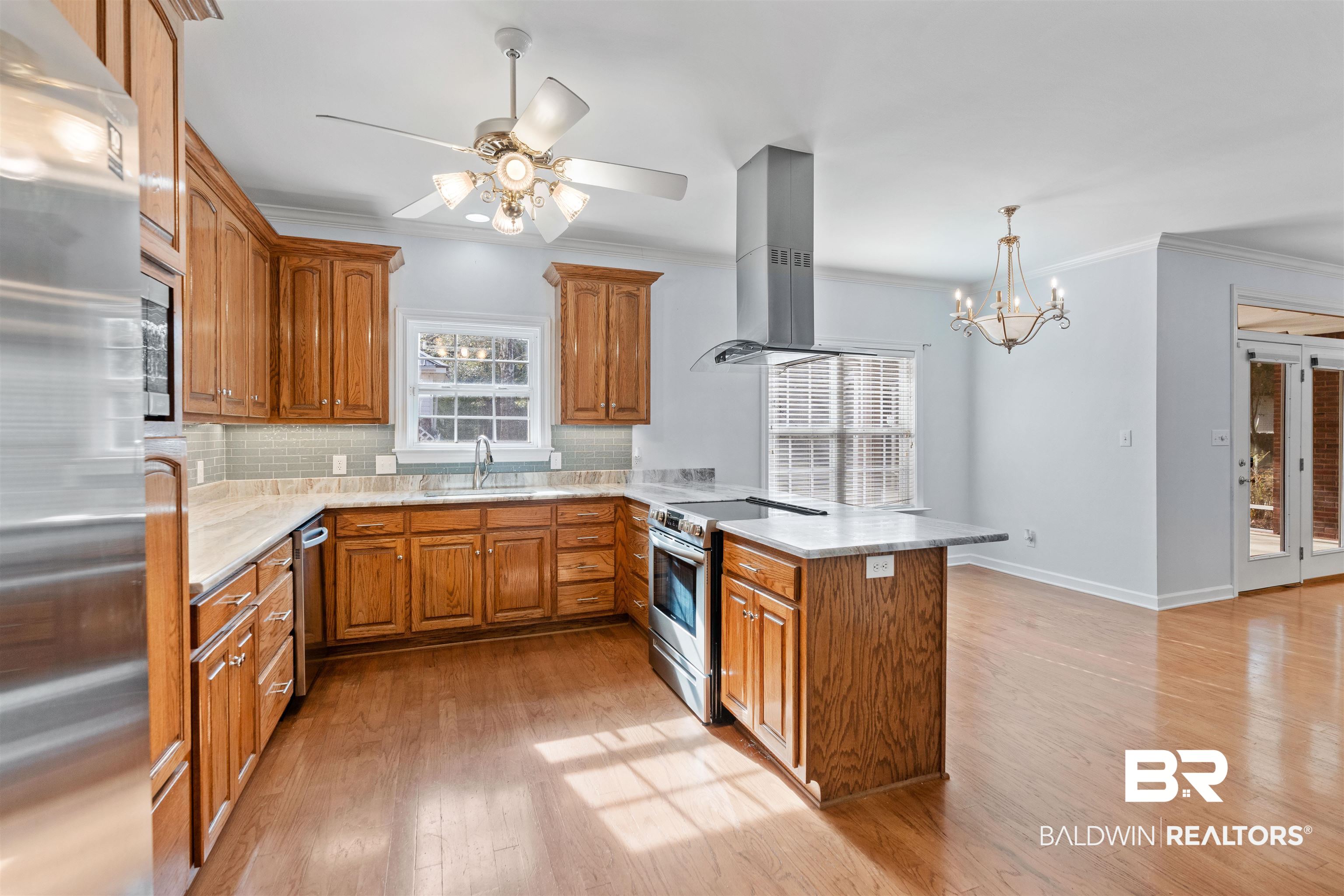 4 Judd Trail Daphne, AL 36527 - Photo 10 of 45 Kitchen with brown cabinets, a sink, island exhaust hood, stainless steel appliances, and a peninsula