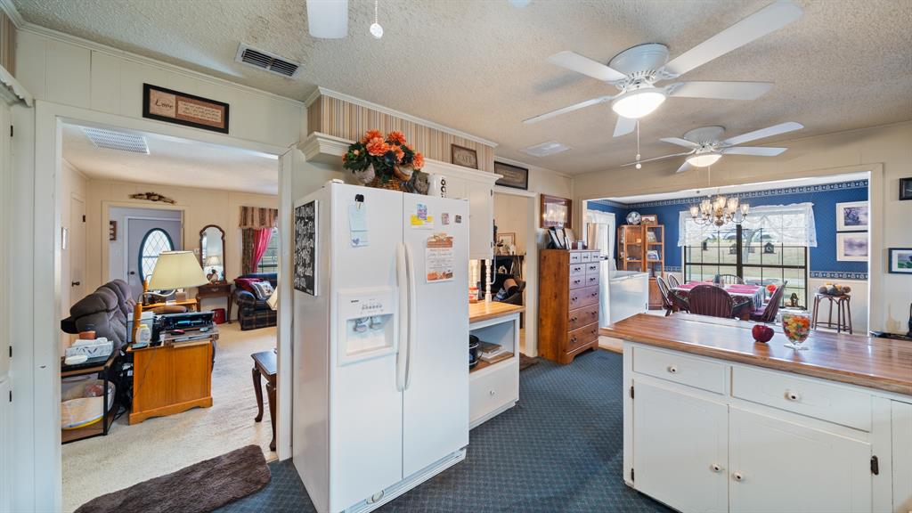 460 VZ County Road Canton, TX 75103 - Photo 11 of 24 Kitchen with a textured ceiling, white refrigerator with ice dispenser, dark carpet, white cabinets, and ceiling fan, there is electricity ran for a dishwasher