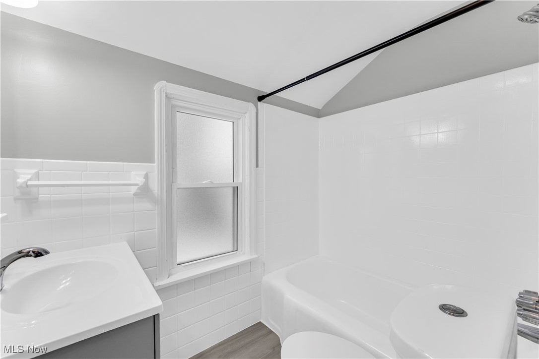 4693 Liberty Road South Euclid, OH 44121 - Photo 25 of 33 Bathroom with tile walls, vanity, shower / washtub combination, vaulted ceiling, and a wainscoted wall