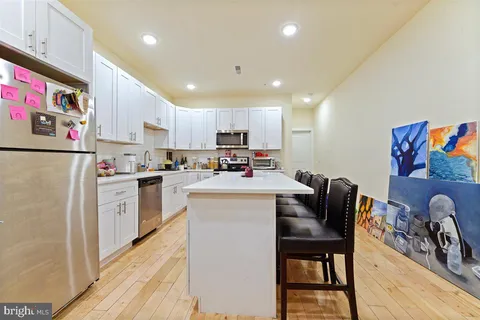 a kitchen with a refrigerator a stove top oven a sink dishwasher and white cabinets with wooden floor