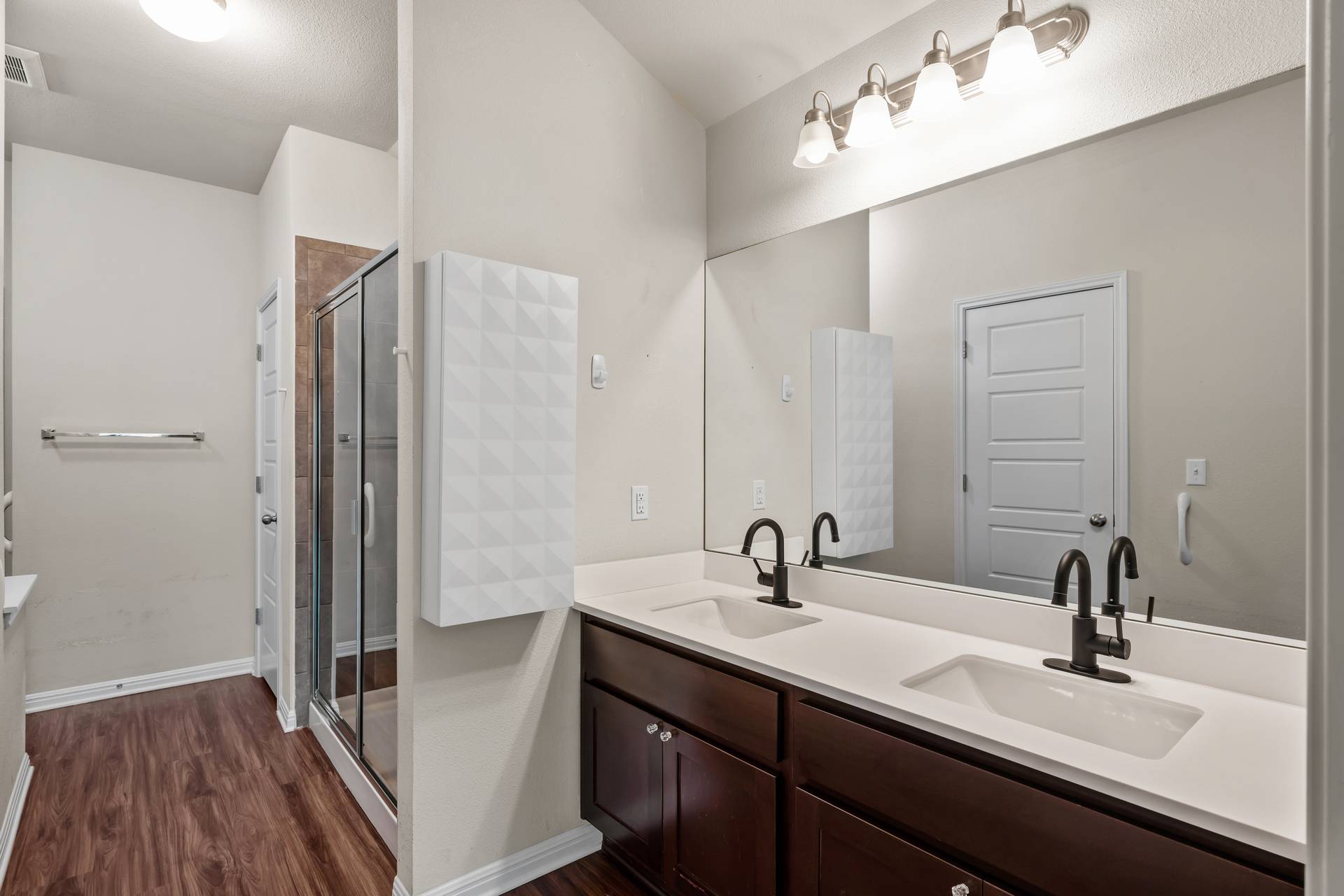 16512 Enamorado Road Manor, TX 78653 - Photo 10 of 31 A well-appointed primary bathroom showcases a double vanity with ample counter space, rich wood cabinetry, and a spacious glass-enclosed shower.