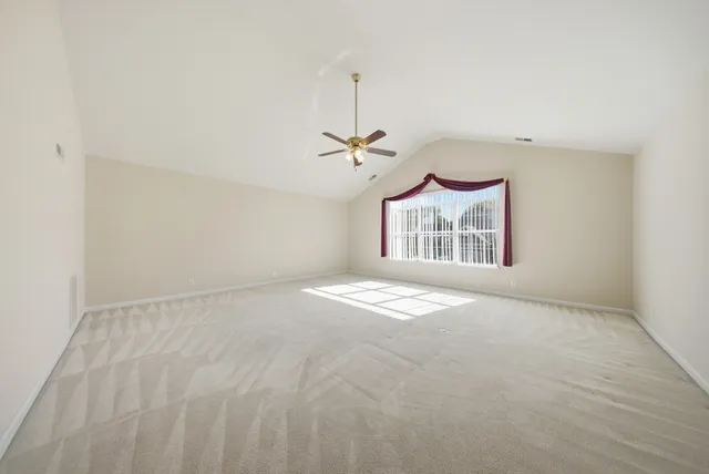 an empty room with window and ceiling fan