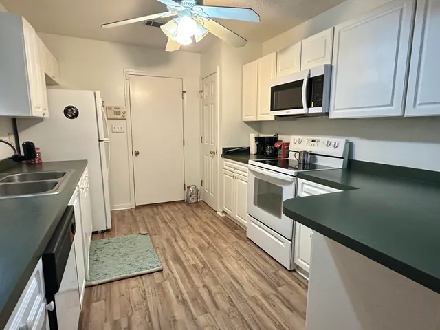 a kitchen with stainless steel appliances granite countertop a sink a stove top oven a refrigerator with wooden floors and cabinets