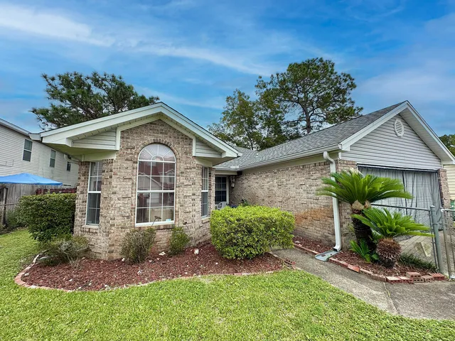 a front view of a house with a yard and potted plants