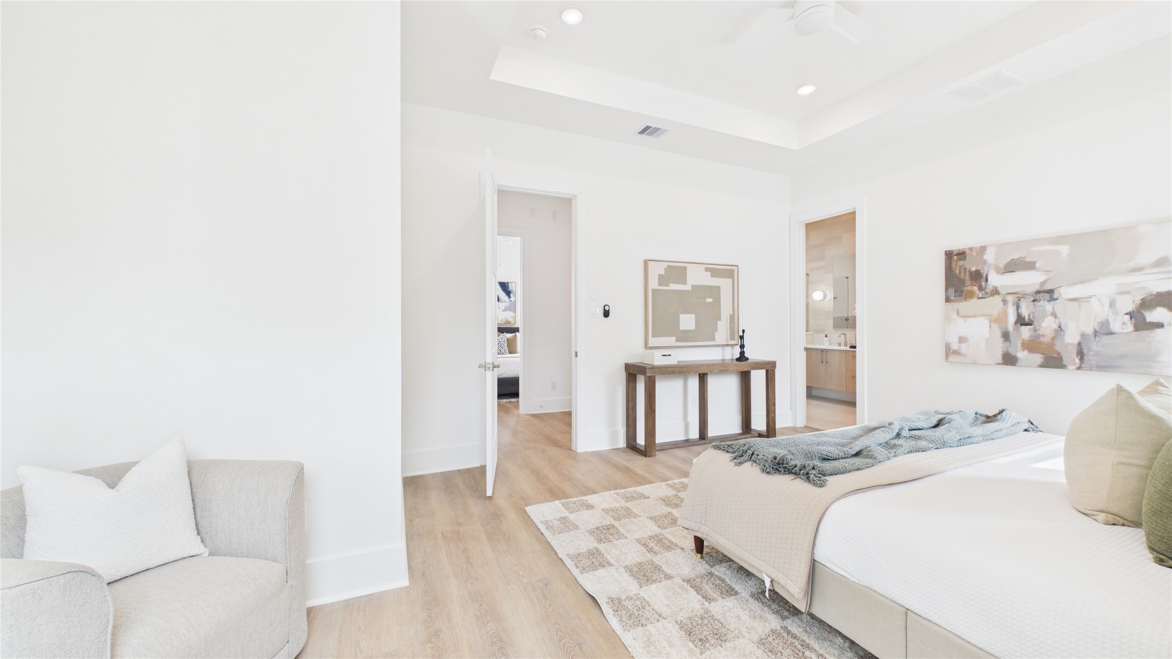 602 Skyland Terrace Way Houston, TX 77009 - Photo 29 of 40 Bright and spacious bedroom with modern decor, featuring light wood flooring, a cozy armchair, and a stylish bed. The room is complemented by abstract art and a clean, open layout leading to an en-suite bathroom.