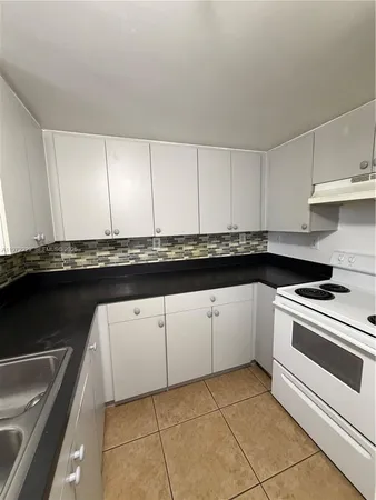 a kitchen with granite countertop a sink a stove and cabinets