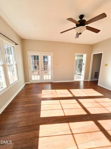 a view of empty room with wooden floor and fan
