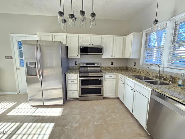 a large kitchen with cabinets a sink and stainless steel appliances