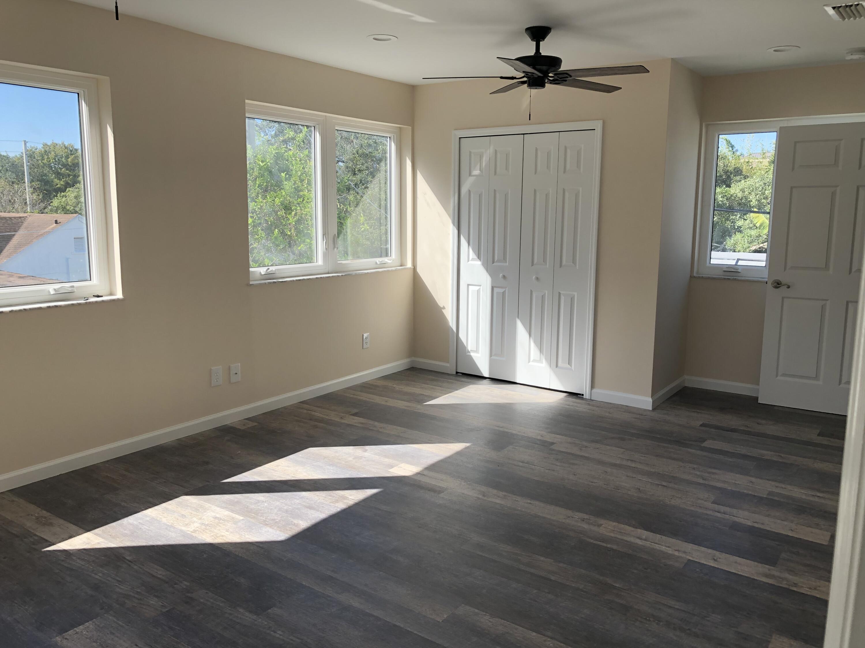 477 Southeast Riverside Drive Stuart, FL 34994 - Photo 3 of 7 an empty room with wooden floor chandelier fan and windows