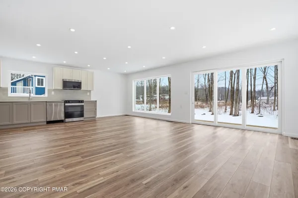 an empty room with wooden floor and windows