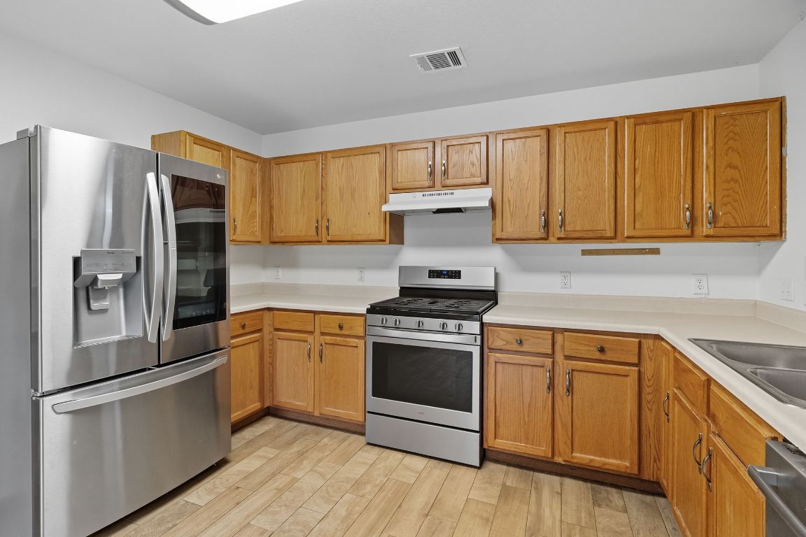 617 Riverway Lane Leander, TX 78641 - Photo 12 of 33 a kitchen with stainless steel appliances granite countertop a stove a refrigerator and a sink with cabinets
