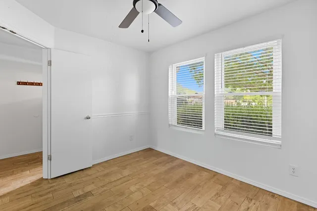 a view of an empty room with a window and wooden floor