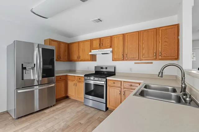 a kitchen with stainless steel appliances granite countertop a refrigerator sink and stove