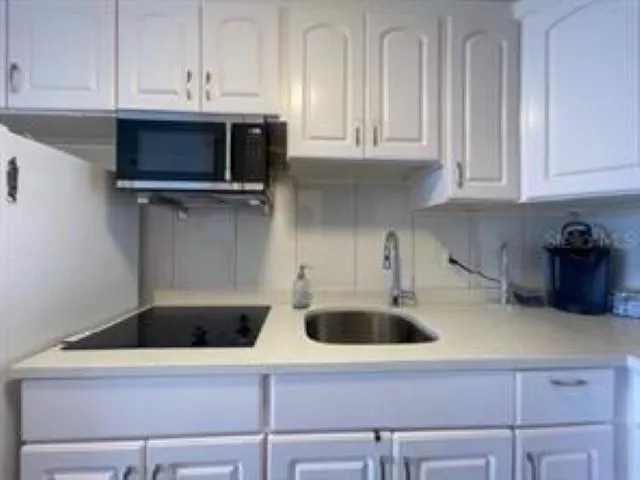a kitchen with white cabinets and sink