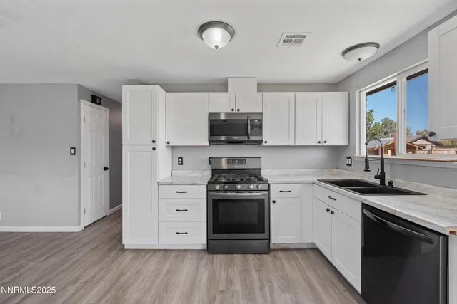 a kitchen with stainless steel appliances granite countertop a stove a sink and a microwave