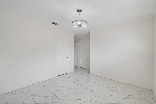 a view of an empty room with chandelier fan