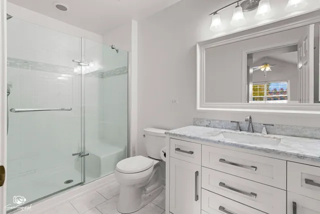 a bathroom with a granite countertop sink toilet a mirror and shower