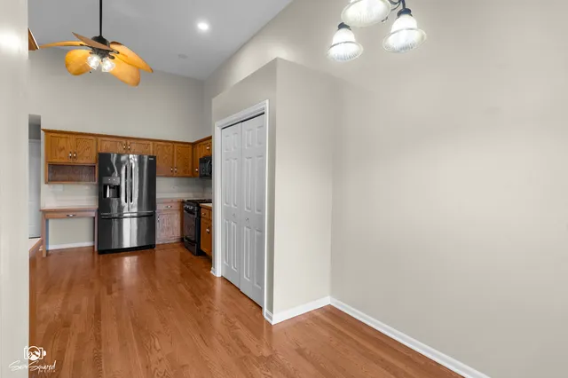 a view of a kitchen with a refrigerator a ceiling fan and wooden floor