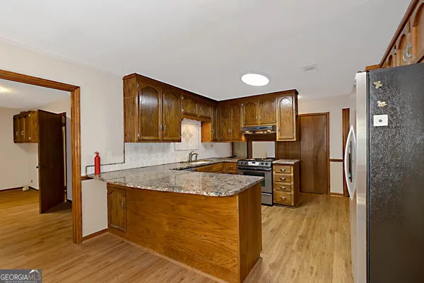 a kitchen with stainless steel appliances granite countertop a refrigerator a stove and a wooden floors
