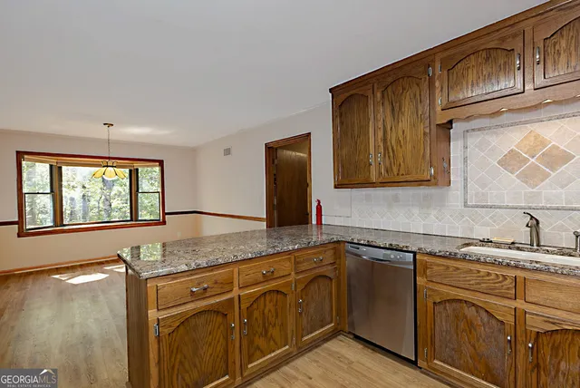 a kitchen with stainless steel appliances granite countertop a sink and cabinets with wooden floor