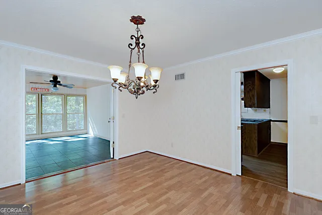 a view of an empty room with a window and wooden floor