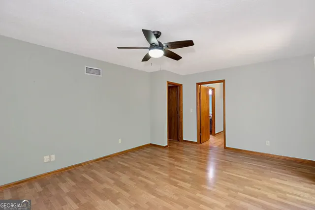 a view of empty room with wooden floor and fan
