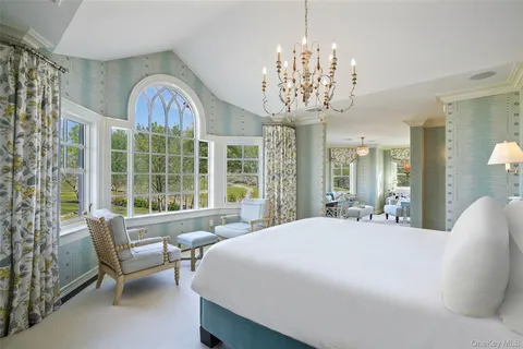 a large bedroom with furniture large window and a chandelier