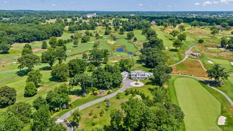 an aerial view of a residential houses with outdoor space and trees all around