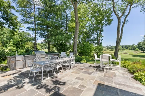 a backyard of a house with table and chairs under an umbrella