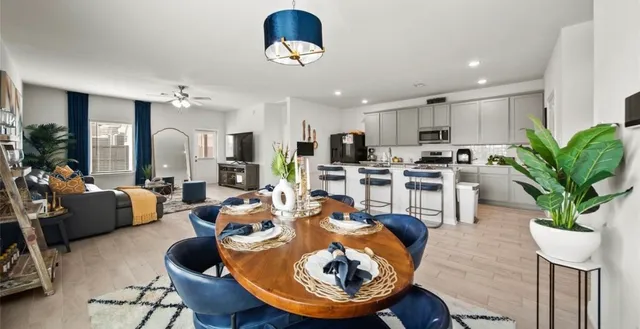a living room with lots of furniture kitchen view and a chandelier