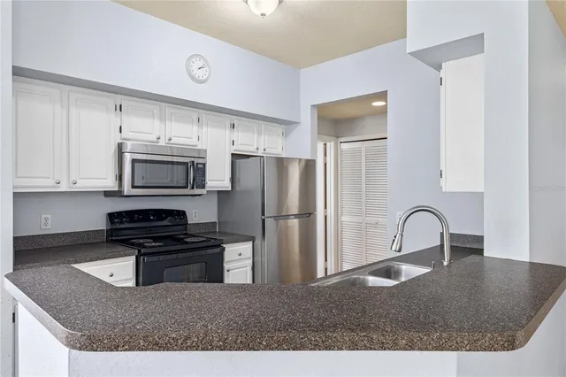 a kitchen with granite countertop a stove a refrigerator and a sink