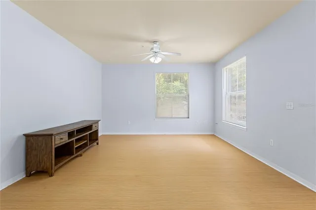 an empty room with windows and ceiling fan