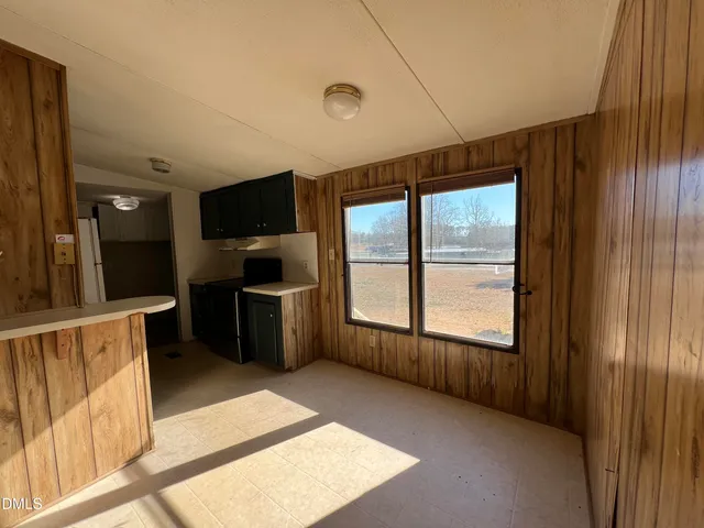 a view of an empty room with a window and a kitchen