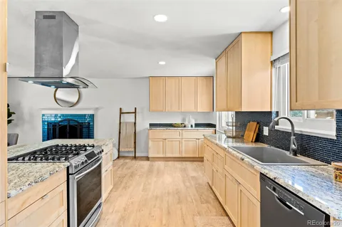 a kitchen with granite countertop a stove a sink and a refrigerator