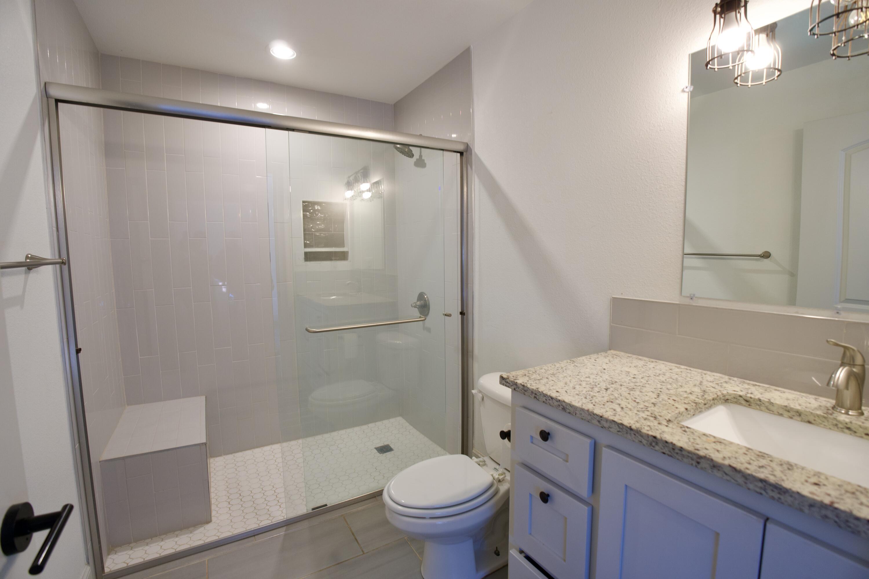2517 52nd Street Lubbock, TX 79413 - Photo 14 of 17 a bathroom with a granite countertop sink toilet and shower