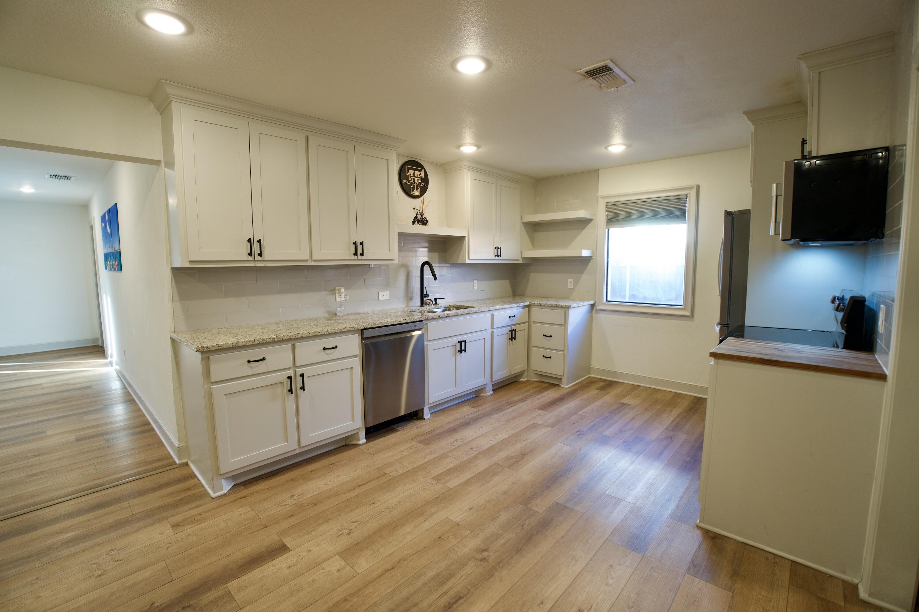 2517 52nd Street Lubbock, TX 79413 - Photo 3 of 17 a kitchen with stainless steel appliances white cabinets a sink a stove a refrigerator and microwave