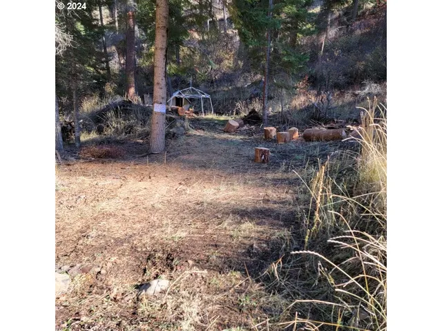 a backyard of a house with table and chairs under an umbrella