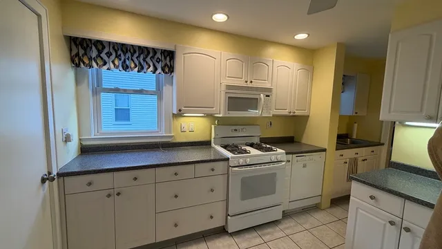 a kitchen with white cabinets and white appliances