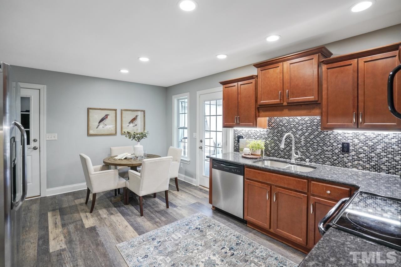 47 Hadleigh Way Fuquay-Varina, NC 27526 - Photo 14 of 37 a large kitchen with stainless steel appliances granite countertop a refrigerator a sink dishwasher a dining table and chair with wooden floor