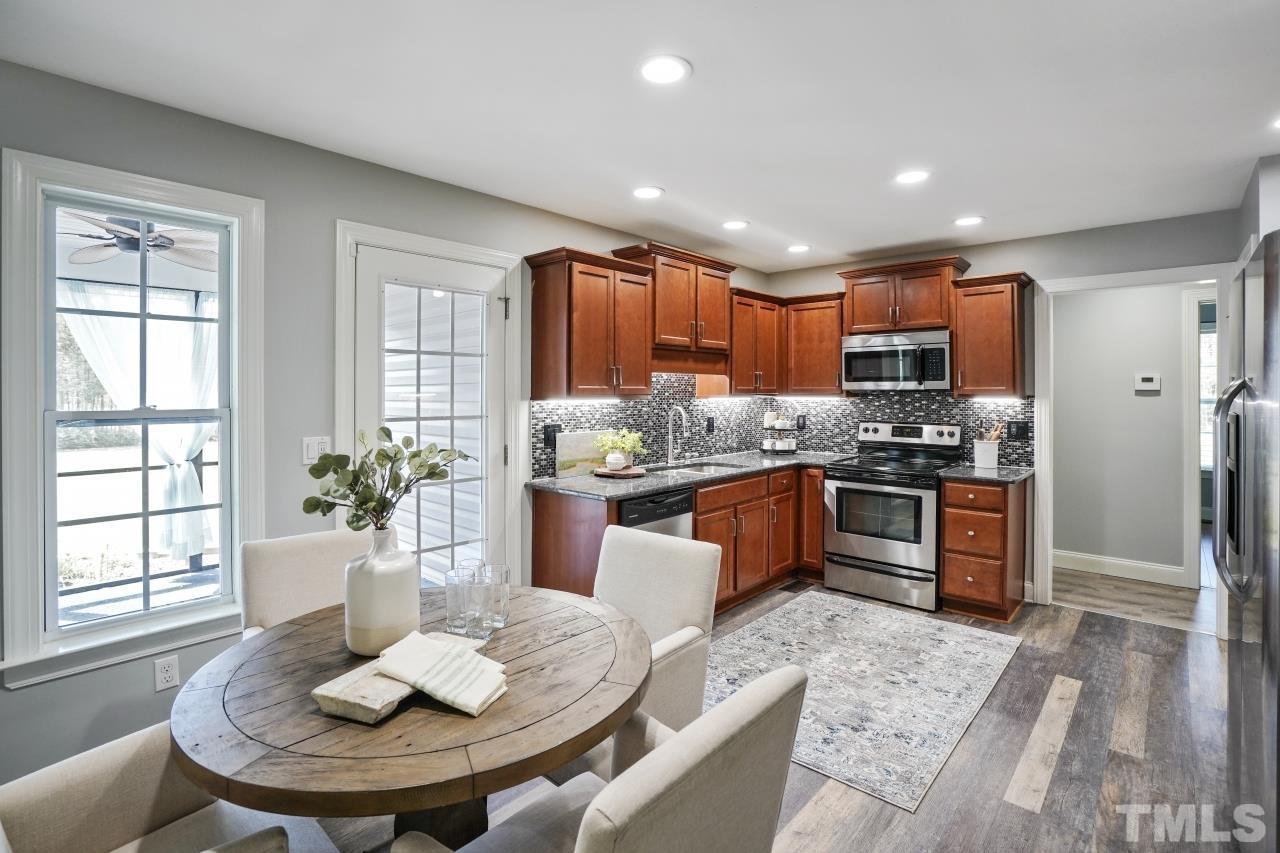 47 Hadleigh Way Fuquay-Varina, NC 27526 - Photo 8 of 37 a kitchen with stainless steel appliances kitchen island granite countertop a refrigerator a sink a stove a dining table and chairs