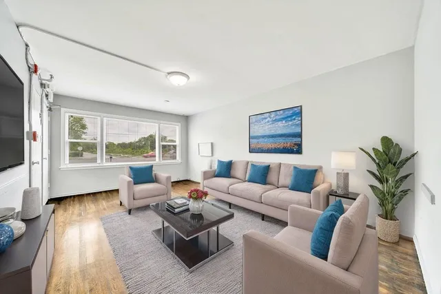 a living room with furniture floor to ceiling window and a flat screen tv