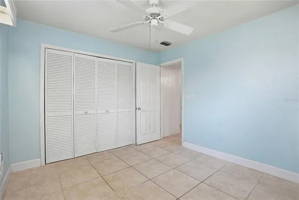 an empty room with chandelier fan and closet