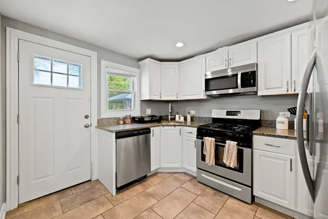 a kitchen with stainless steel appliances granite countertop a stove a sink and a microwave