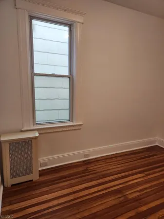 an empty room with wooden floor and cabinet