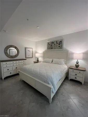 a bedroom with a bed and a lamp on dresser