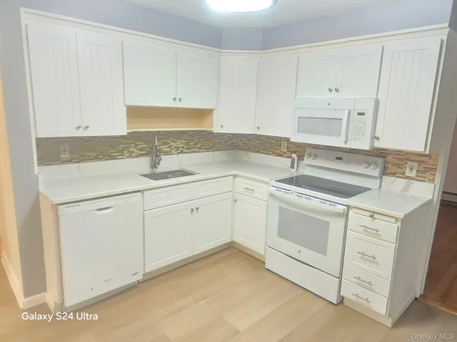 a kitchen with white cabinets appliances and sink